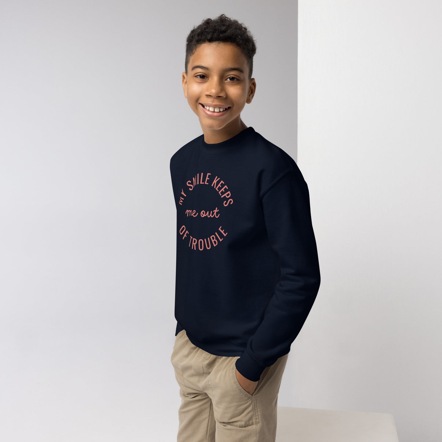 youth crew neck sweatshirt with 'My Smile Keeps Me Out of Trouble' text design